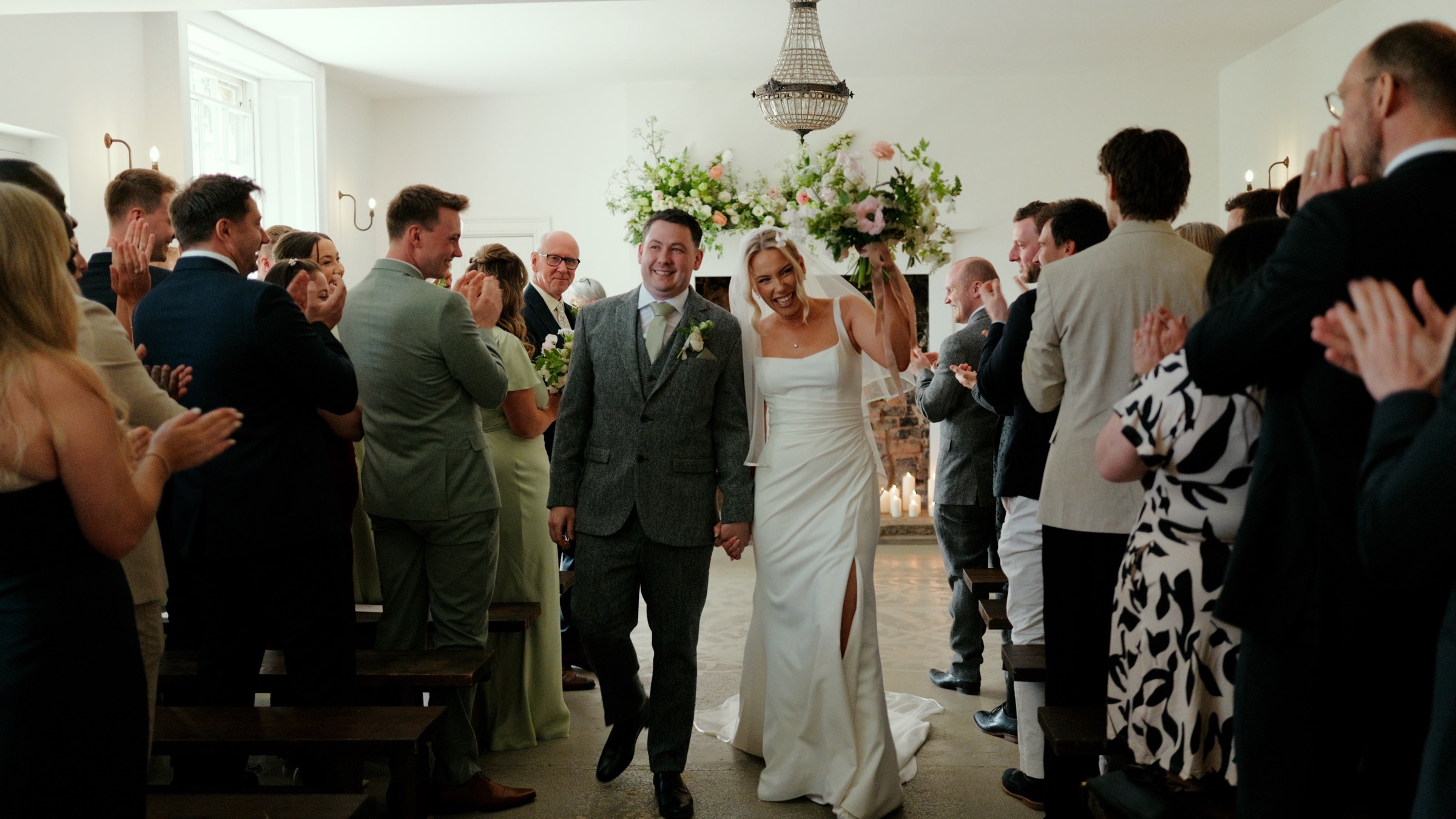 A bride and groom walking back down the aisle at Aswarby Rectory as their guests clap and cheer