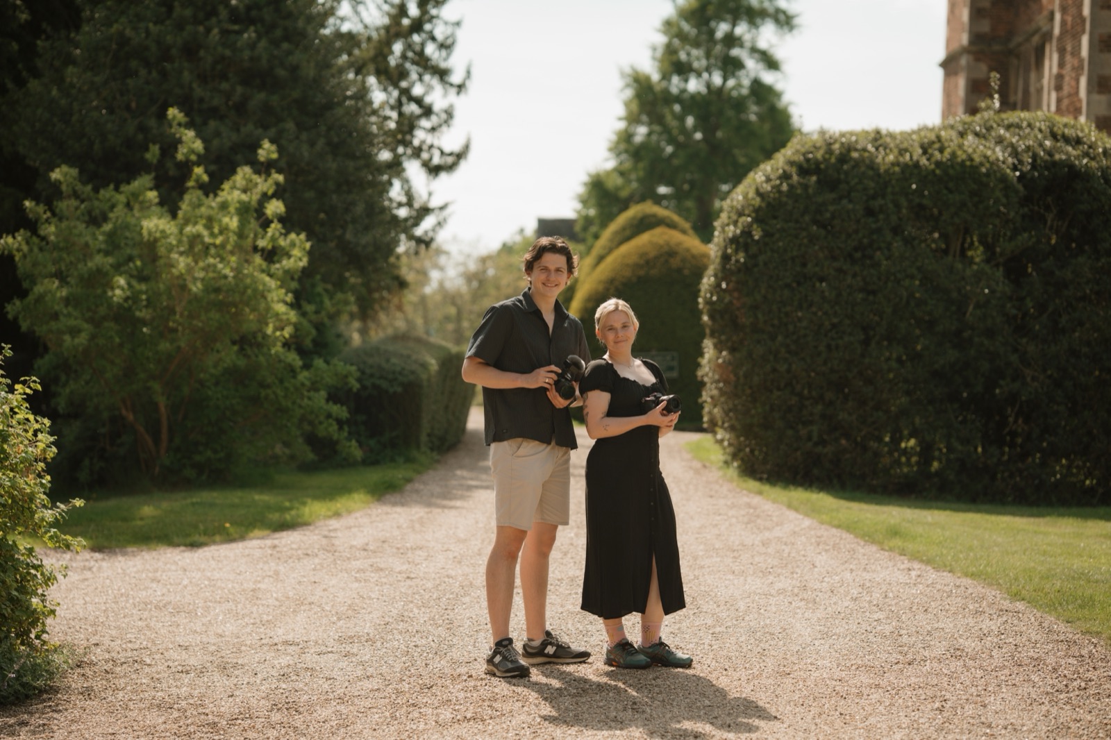 George Hughes and Chloe Gelsthorpe with their cameras in the gardens at Doddington Hall, wedding videographer and photographer