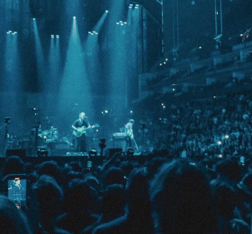 A band on stage under blue lights, seen from the crowd